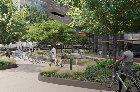 A design rendering shows bicycle racks and people walking their bicycles on a sidewalk area surrounded by lush trees and vegetation outside of the Pavilion.